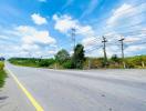 Paved road with surrounding greenery under a clear blue sky