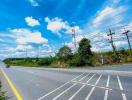 Wide road with clear blue sky and lush greenery on the sides