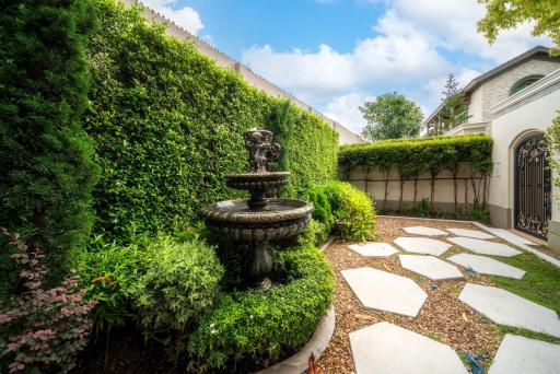 Elegant garden pathway with lush greenery and a classic fountain