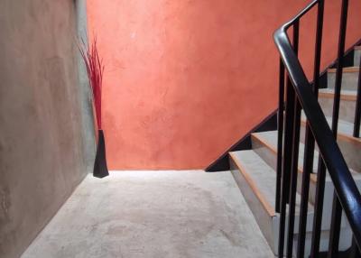 Modern staircase with red accent wall and metal railing