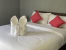 Cozy bedroom interior with neatly arranged pillows and decorative towel swans on the bed