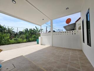 Spacious covered patio with tiled flooring and white fencing