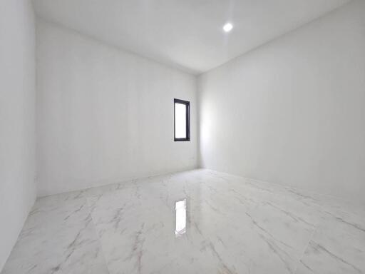 Empty white room with marble flooring and a single window