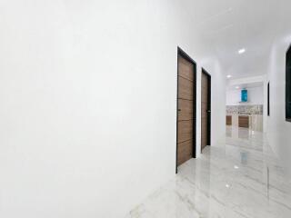 Spacious white hallway with marble flooring and modern wooden doors