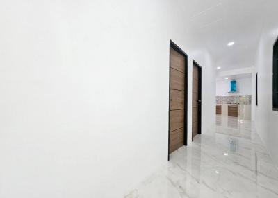 Spacious white hallway with marble flooring and modern wooden doors