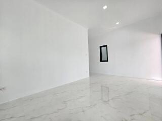 Spacious empty room with white marble flooring and bright lighting