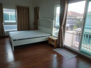 Spacious bedroom with wooden flooring and natural light