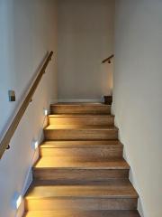 Elegant wooden staircase with wall lights