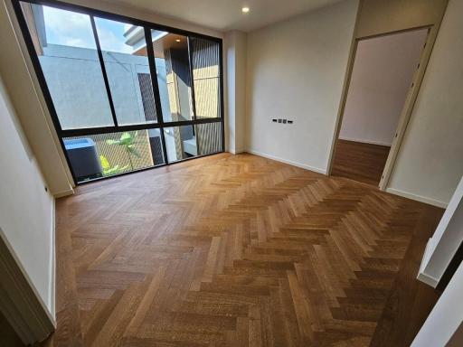 Spacious unfurnished bedroom with herringbone pattern wood flooring and large windows