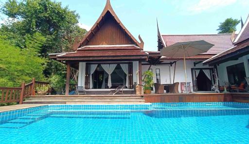 Traditional style house exterior with swimming pool and lush greenery