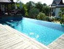 Private swimming pool with wooden deck and view of the garden