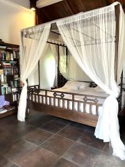 Spacious bedroom with a four-poster bed and a private library