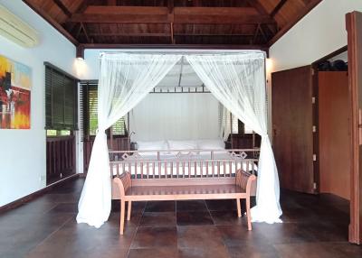 Spacious bedroom with a large bed, high ceiling, and wooden furniture
