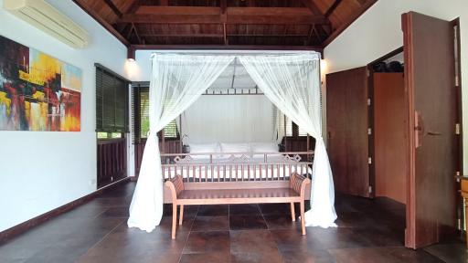 Spacious bedroom with a large bed, high ceiling, and wooden furniture