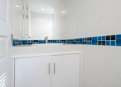 Modern bathroom interior with white cabinetry and blue accent tiles