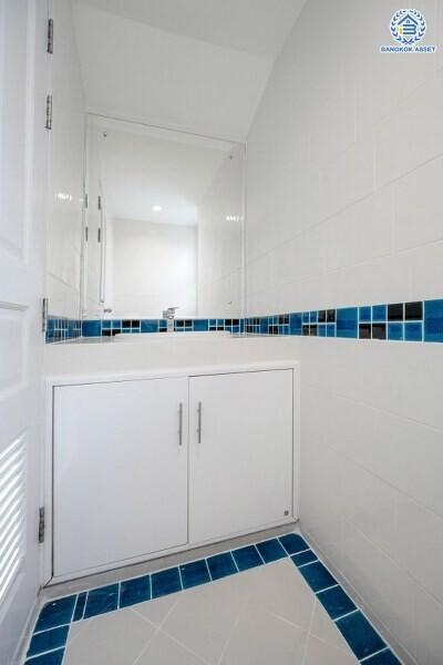 Modern bathroom interior with white cabinetry and blue accent tiles