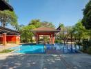 Luxurious outdoor swimming pool area with pavilion and lush greenery