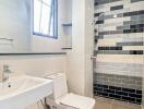 Modern bathroom interior with a white ceramic suite and contrasting black and white tiled wall