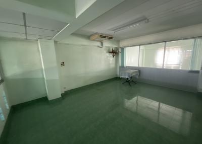 Spacious empty interior of a building with large windows and green flooring