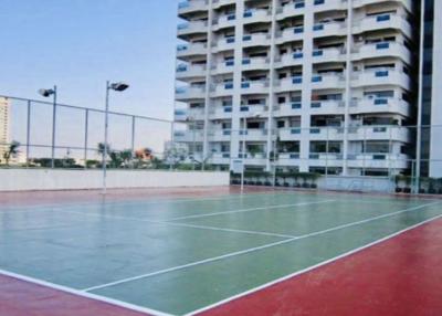 Outdoor tennis court with apartment building in the background