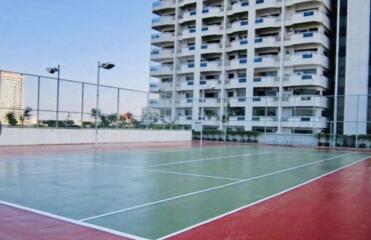 Outdoor tennis court with apartment building in the background