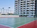 Outdoor tennis court with apartment building in the background