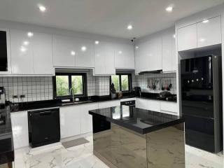 Modern spacious kitchen with marble floors, black countertops, and stainless steel appliances