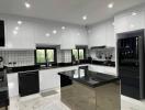 Modern spacious kitchen with marble floors, black countertops, and stainless steel appliances