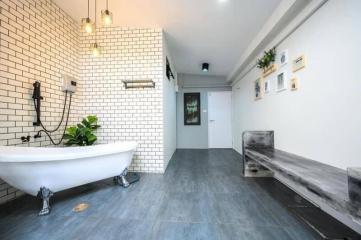 Spacious bathroom with a freestanding tub, modern lighting, and decorative plants