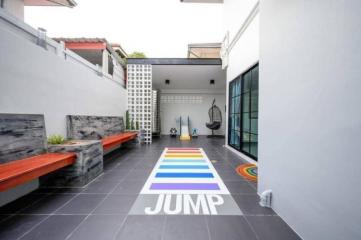 Modern outdoor space with colorful jump hopscotch game painted on the floor, seating areas, and decorative elements
