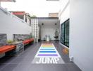 Modern outdoor space with colorful jump hopscotch game painted on the floor, seating areas, and decorative elements