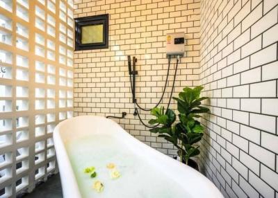 Modern bathroom with white brick-style tiles and freestanding bathtub