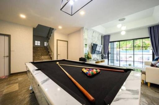 Spacious living room with pool table and abundant natural light