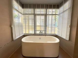 Modern bathroom with a freestanding bathtub and large window with blinds