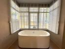 Modern bathroom with a freestanding bathtub and large window with blinds