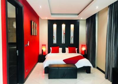 Modern bedroom with bold red accent wall, king-sized bed, and elegant decor