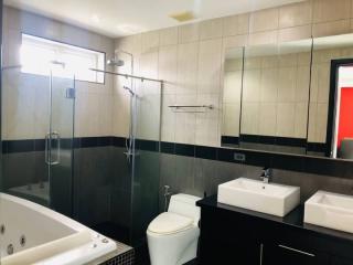 Modern bathroom interior with a white bathtub, ceramic sink, toilet, and glass shower enclosure