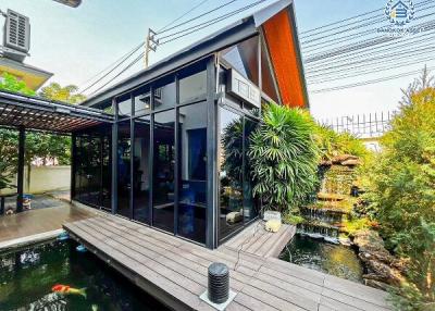 Modern house extension with large glass windows and koi pond