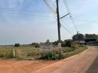 Rural landscape with empty plot and signboard beside a dirt road