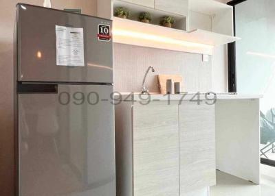 Modern compact kitchen with stainless steel refrigerator, white cabinetry, and stylish backsplash