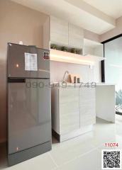 Modern compact kitchen with stainless steel refrigerator, white cabinetry, and stylish backsplash