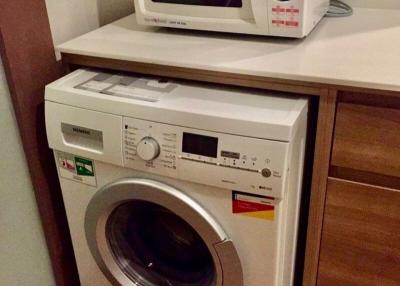 Compact laundry room with modern washer and microwave