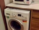 Compact laundry room with modern washer and microwave