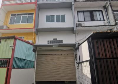 Three-story residential building facade with parking space