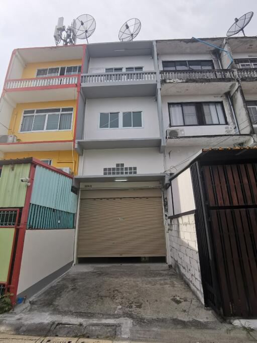 Three-story residential building facade with parking space