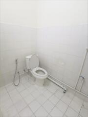 Neat white tiled bathroom with toilet and hand-held shower