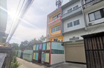 Colorful multi-story residential building exterior with a garage and surrounded by a metal fence