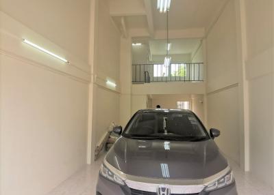 Spacious garage with tiled floor, fluorescent lighting, and a modern car parked inside