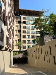 Exterior view of a modern residential apartment building with balconies and a clear blue sky