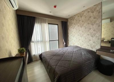 Spacious and modern bedroom with a large bed, patterned feature wall, and ample natural light